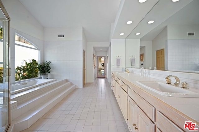 bathroom featuring double sink vanity, a relaxing tiled tub, and tile patterned flooring