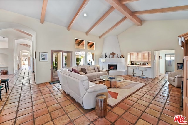 tiled living room featuring high vaulted ceiling, a fireplace, and beam ceiling