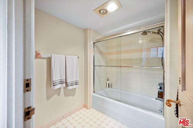 bathroom with bath / shower combo with glass door and tile patterned flooring