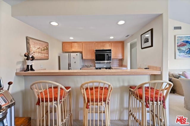 kitchen with tasteful backsplash, light brown cabinets, lofted ceiling, carpet flooring, and white fridge