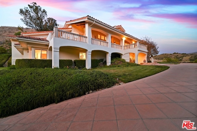 view of front of house with a balcony and a lawn