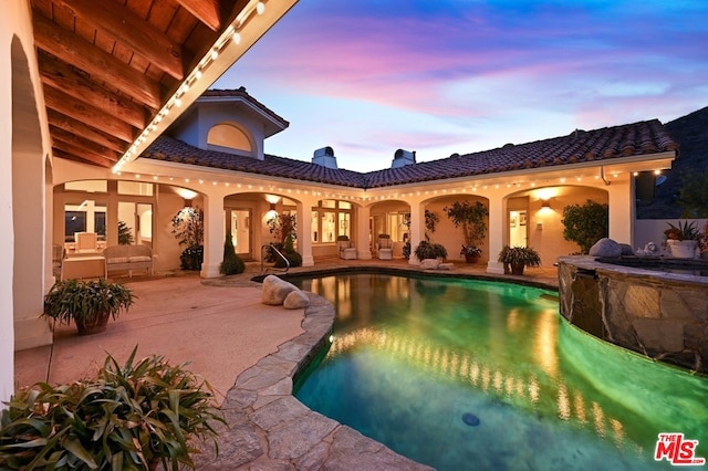 pool at dusk featuring a patio area