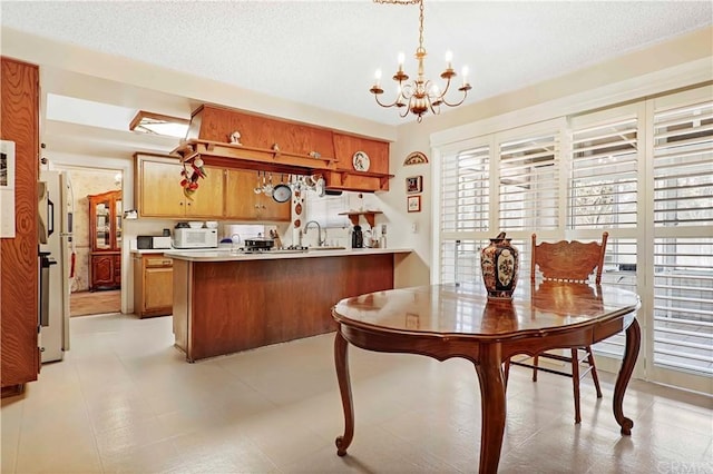 kitchen featuring light tile flooring, pendant lighting, a notable chandelier, a textured ceiling, and kitchen peninsula