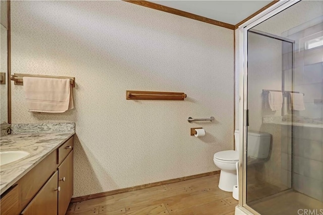 bathroom with toilet, ornamental molding, a shower with door, wood-type flooring, and vanity