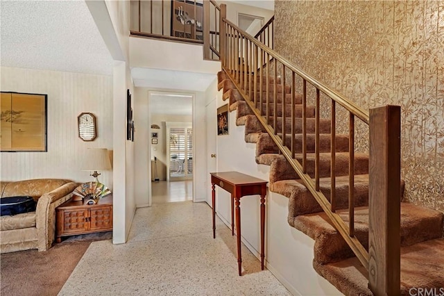 staircase with a textured ceiling and a towering ceiling