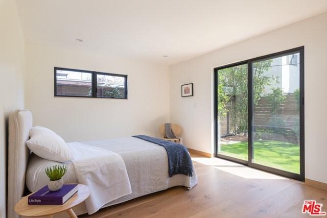 bedroom featuring access to exterior, light wood-type flooring, and multiple windows