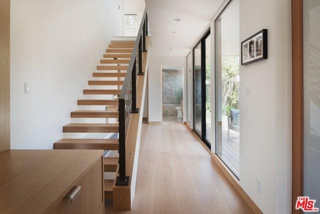 stairs with a wall of windows and light hardwood / wood-style flooring