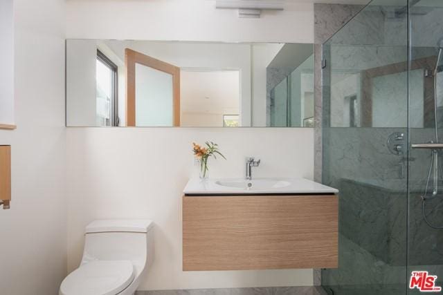 bathroom with toilet, a shower with door, and vanity