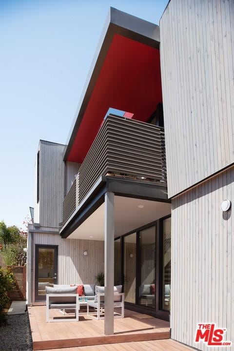 rear view of house featuring a balcony and an outdoor hangout area