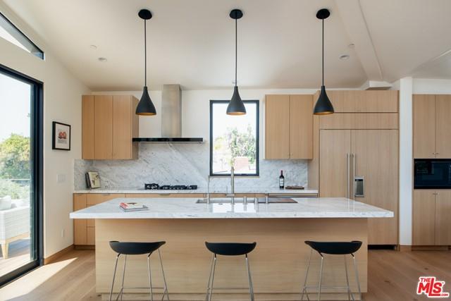 kitchen featuring an island with sink, tasteful backsplash, light hardwood / wood-style flooring, and wall chimney range hood