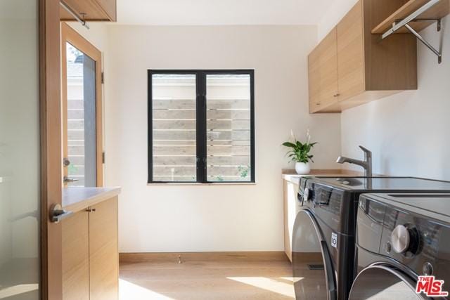 washroom with light hardwood / wood-style floors, cabinets, and separate washer and dryer