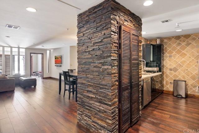 kitchen featuring dishwasher, dark hardwood / wood-style flooring, light stone countertops, and tile walls