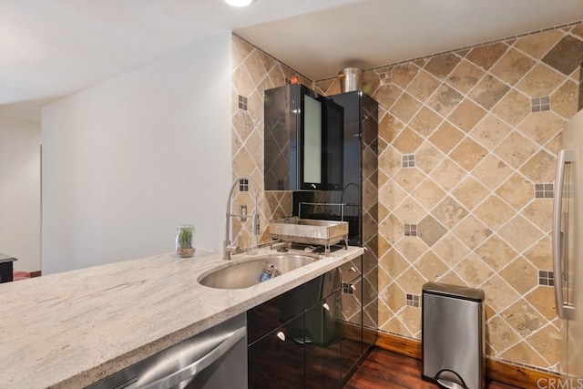 kitchen with dark hardwood / wood-style flooring, light stone counters, sink, and tile walls