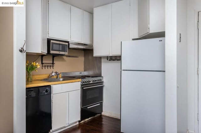 kitchen with white fridge, dark hardwood / wood-style flooring, stainless steel microwave, black dishwasher, and white cabinetry