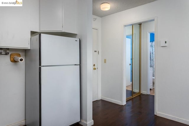 kitchen featuring a textured ceiling, white fridge, dark hardwood / wood-style floors, and white cabinetry