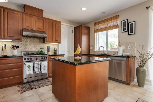 kitchen with sink, stainless steel appliances, dark stone countertops, light tile floors, and a kitchen island