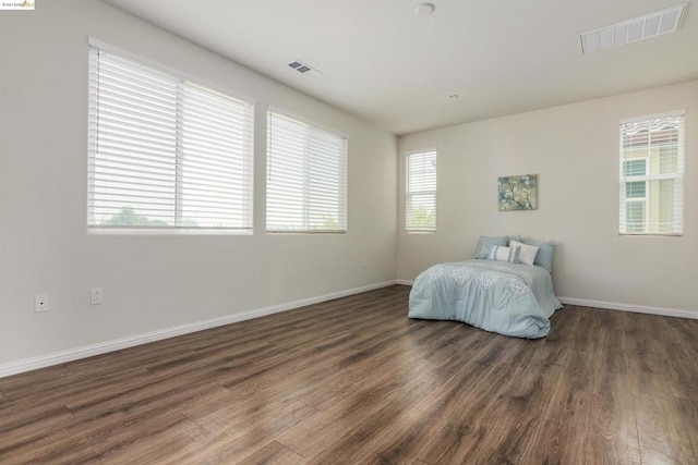 unfurnished bedroom featuring dark hardwood / wood-style flooring and multiple windows