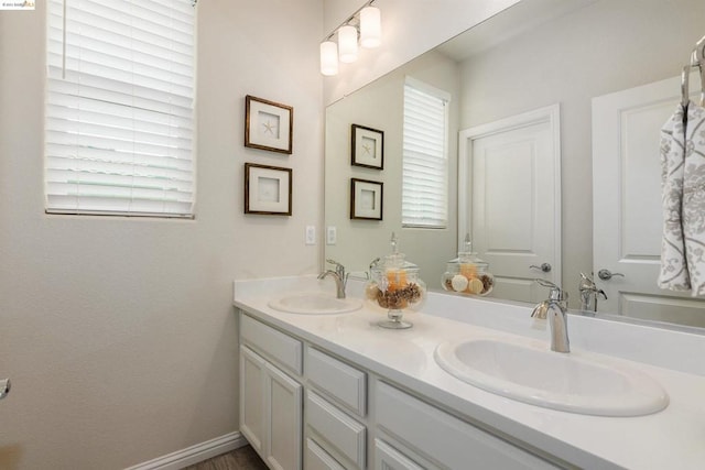 bathroom featuring a healthy amount of sunlight, vanity with extensive cabinet space, and double sink