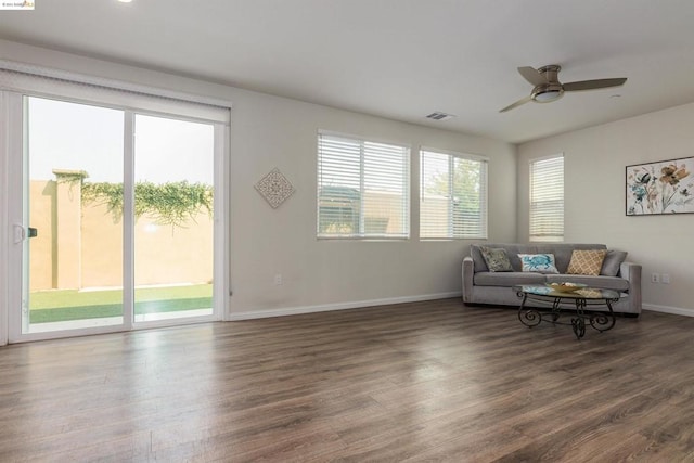 living room with a healthy amount of sunlight, ceiling fan, and dark wood-type flooring