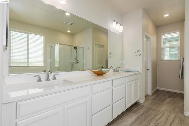 bathroom with double sink vanity, a wealth of natural light, and an enclosed shower