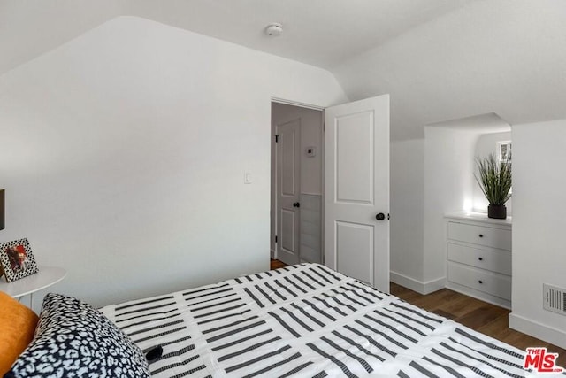 bedroom with lofted ceiling and dark hardwood / wood-style floors