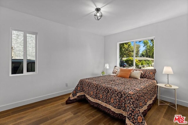 bedroom with multiple windows and dark wood-type flooring