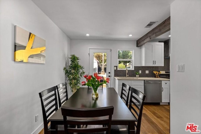 dining space with beamed ceiling, light hardwood / wood-style flooring, and sink