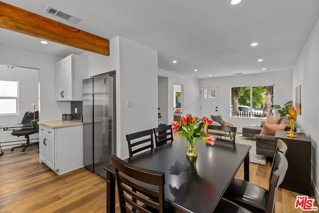 dining space featuring beamed ceiling and light hardwood / wood-style floors