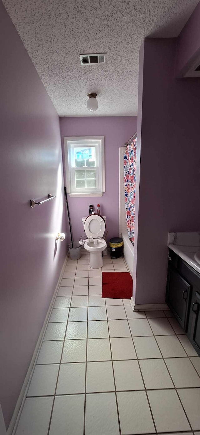 6567 NE Montrose Trl, Tallahassee, FL 32309 - bathroom featuring a textured ceiling, tile patterned flooring, toilet, vanity, and baseboards