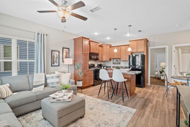 living room featuring ceiling fan and light hardwood / wood-style flooring