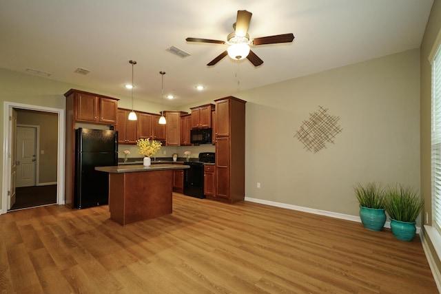 kitchen with hardwood / wood-style floors, black appliances, ceiling fan, decorative light fixtures, and a kitchen island