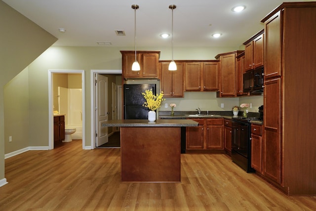 kitchen featuring sink, a center island, light hardwood / wood-style flooring, decorative light fixtures, and black appliances