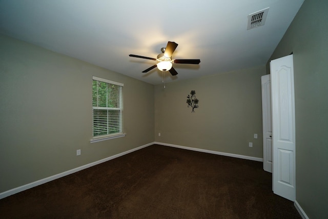 spare room with dark colored carpet and ceiling fan