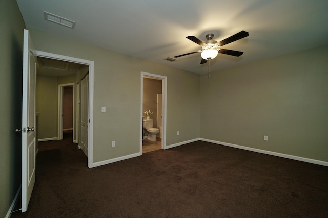 unfurnished bedroom featuring ensuite bath, ceiling fan, and dark carpet