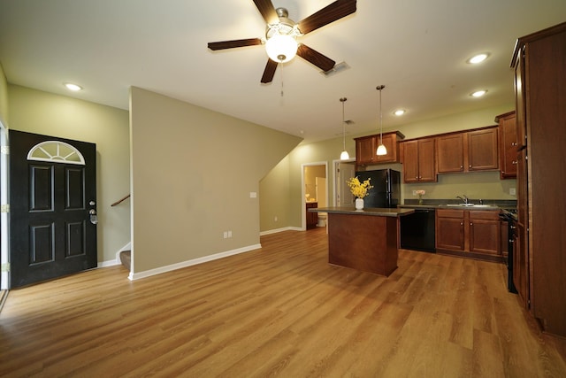 kitchen featuring sink, decorative light fixtures, a kitchen island, black appliances, and hardwood / wood-style flooring