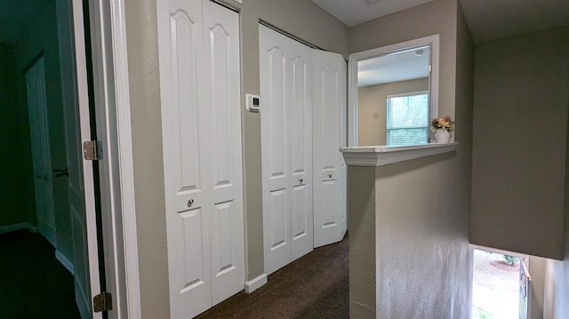 hallway with dark colored carpet