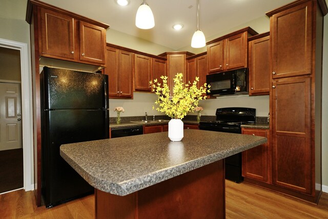 kitchen featuring pendant lighting, a kitchen island, black appliances, and light hardwood / wood-style floors