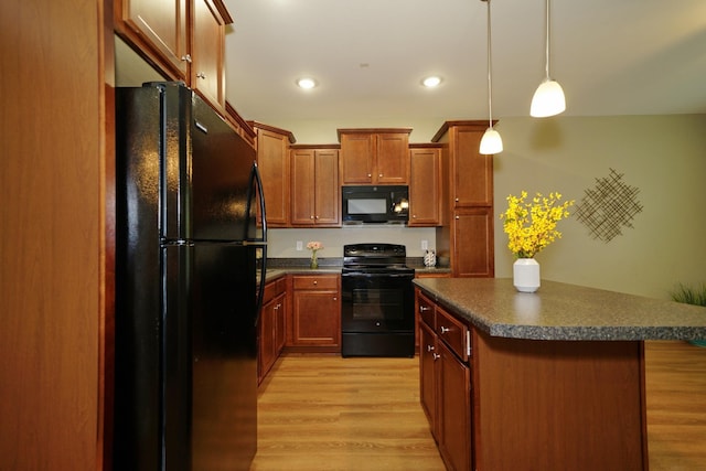 kitchen with hanging light fixtures, a center island, black appliances, and light hardwood / wood-style floors