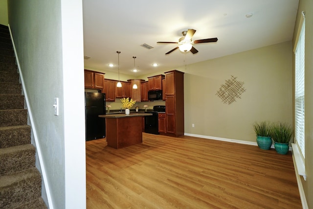 kitchen featuring hardwood / wood-style floors, decorative light fixtures, a kitchen island, and black appliances