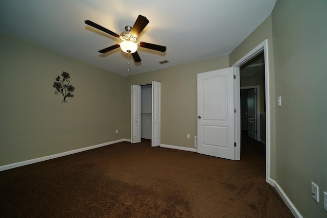 unfurnished bedroom featuring ceiling fan, dark carpet, and a closet