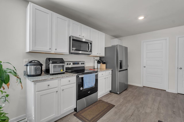 kitchen featuring appliances with stainless steel finishes, light hardwood / wood-style flooring, white cabinetry, and light stone countertops