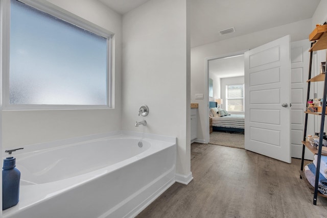 bathroom with hardwood / wood-style floors and a tub to relax in