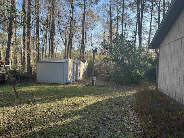 view of yard featuring an outbuilding, a storage unit, and fence