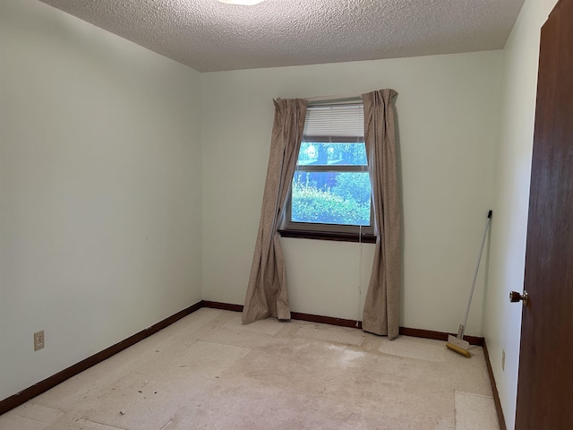 empty room with baseboards, a textured ceiling, and light carpet