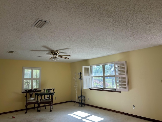 spare room with a ceiling fan, a textured ceiling, baseboards, and visible vents