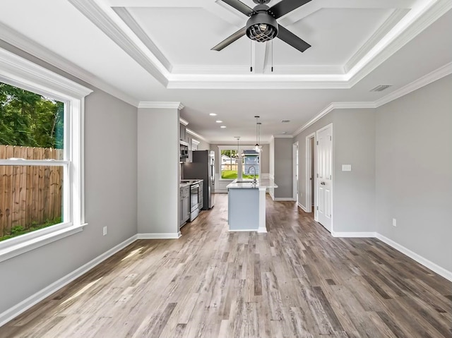 unfurnished living room with light hardwood / wood-style flooring, ceiling fan with notable chandelier, a raised ceiling, and crown molding