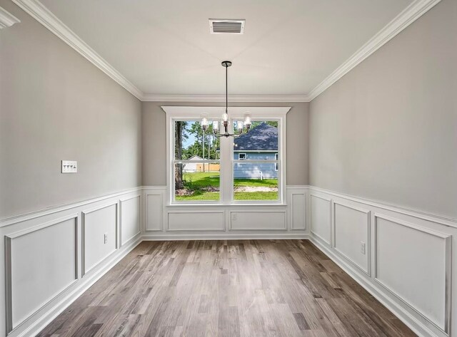 unfurnished dining area with light hardwood / wood-style flooring, a chandelier, and crown molding