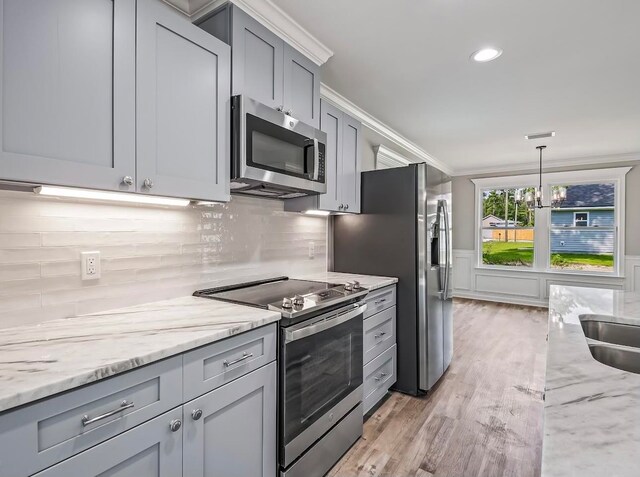 kitchen with appliances with stainless steel finishes, hanging light fixtures, a chandelier, light hardwood / wood-style flooring, and gray cabinets