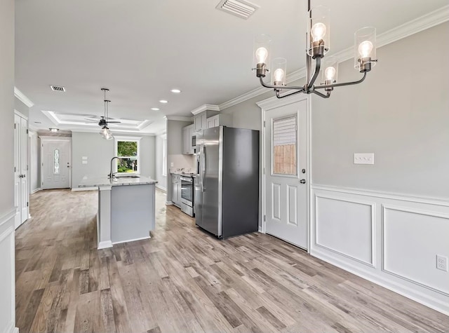 kitchen with pendant lighting, appliances with stainless steel finishes, crown molding, and light hardwood / wood-style flooring