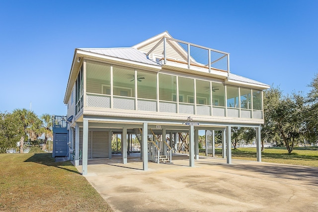 beach home featuring ceiling fan, a carport, a sunroom, and a front yard